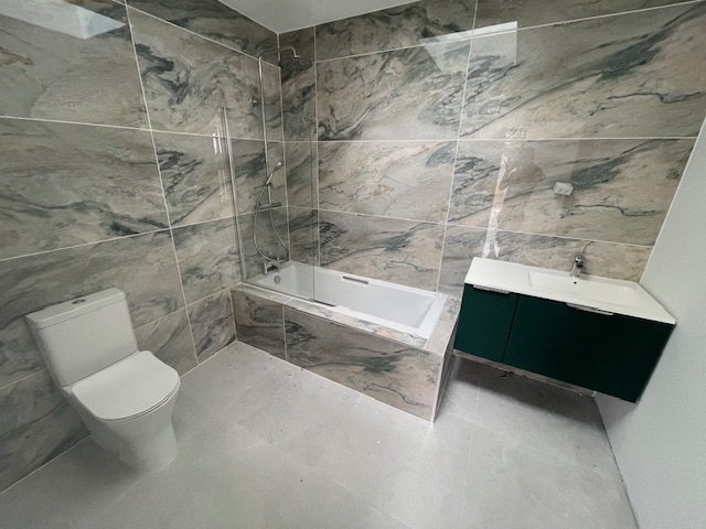 Full bathroom fit-out with marble-effect tiling and bath