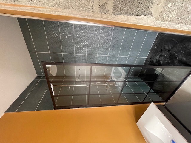 Framed shower enclosure with dark tiling